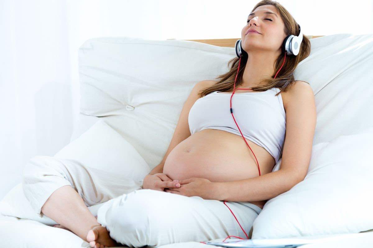 Donna incinta stesa ascolta la musica