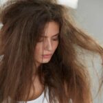 donna che guarda e tocca capelli crespi